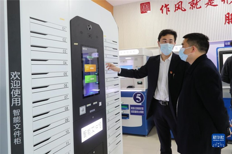 上海市闵行区七宝镇社区事务受理服务中心的工作人员（左）向前来办事的居民介绍智能文件柜的使用方法（2021年3月3日摄）。新华社记者 方喆 摄