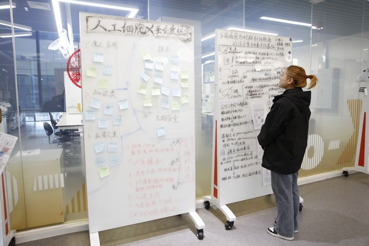 在深圳零一学院，一名工作人员阅读查看学生编绘的研究汇报材料（2024年3月1日摄）。新华社记者 洪泽华 摄