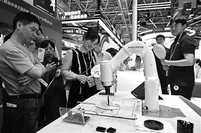 图为观众在第七届数字中国建设峰会现场体验区观看AI书法机器人在扇面上写字。新华社记者 林善传 摄